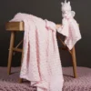 Plush Βρεφική Κουβέρτα Ροζ απλωμένη σε τραπέζι με αρκουδάκι και πανάκι
