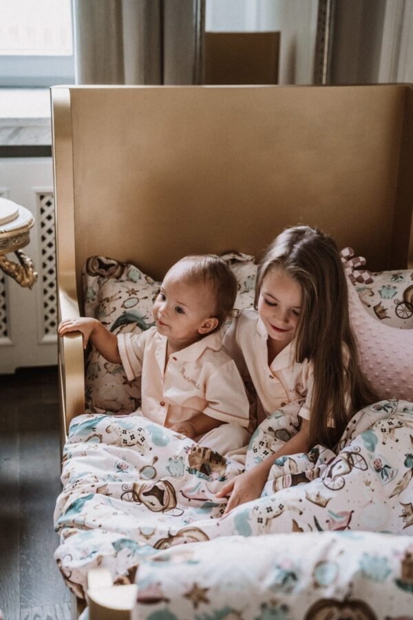 Princess Βρεφικό Πάπλωμα με σχέδιο καστράκια να σκεπάζει ένα παιδάκι κι ένα βρέφος σε παιδικό κρεβάτι