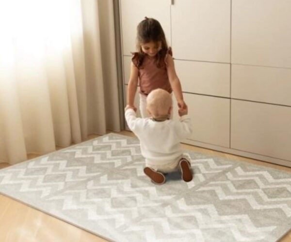 Puzzle Play Mat Kilim Feather Gray, πάνω στο οποίο παίζουν δύο παιδάκια
