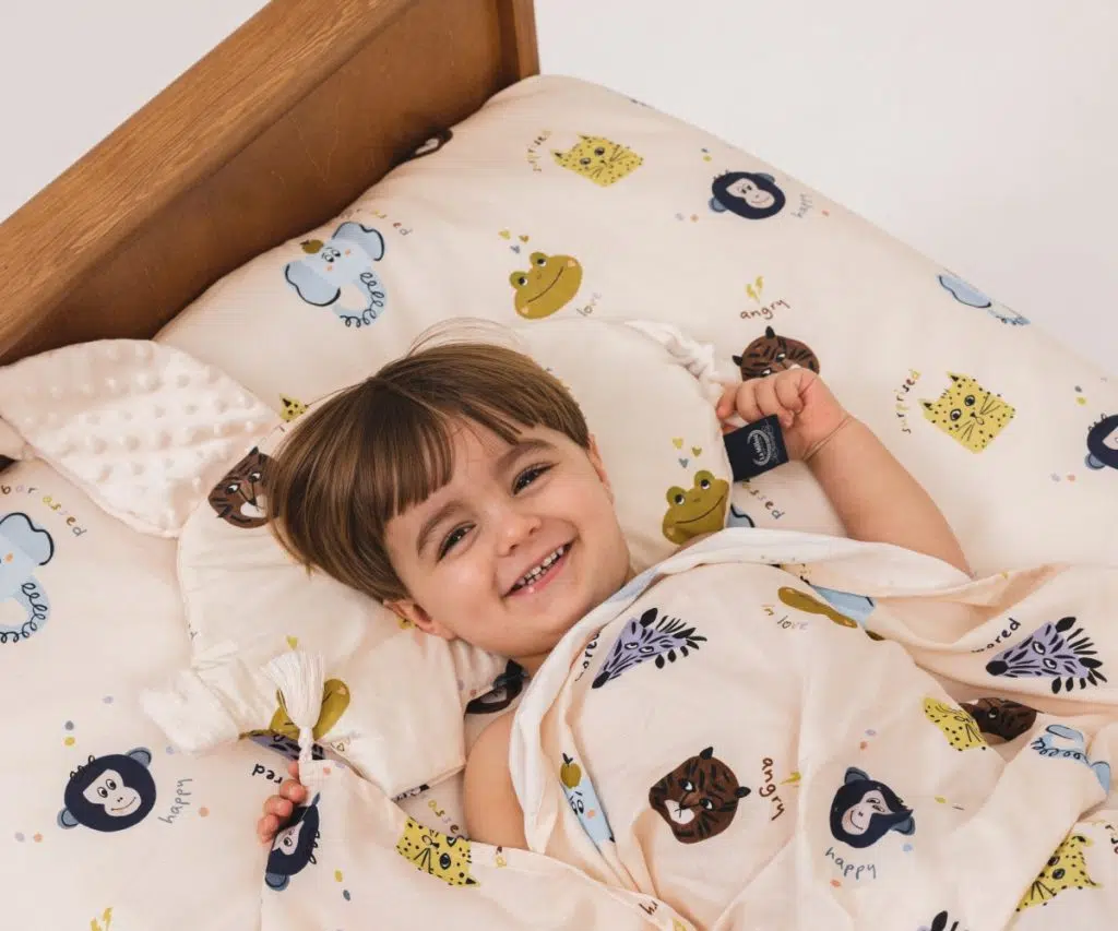 Friends Sleepy Pig Ecru, πάνω στο οποίο ξαπλώνει ένα παιδάκι