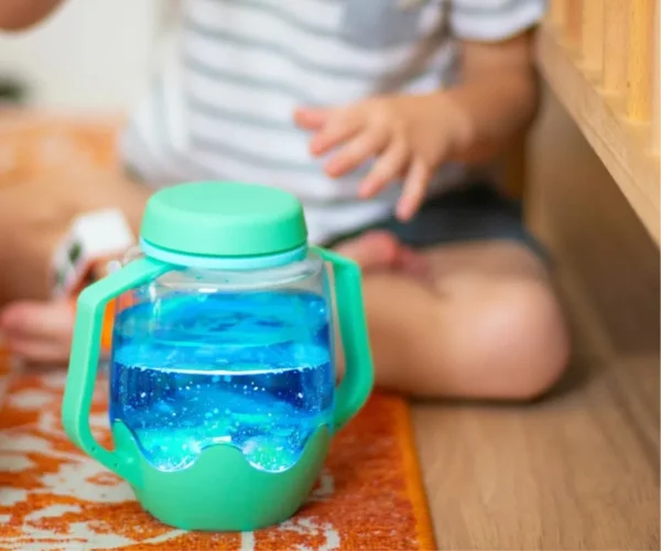 Sensory Jar Green Lucky Charm, με το οποίο παίζει ένα βρέφος