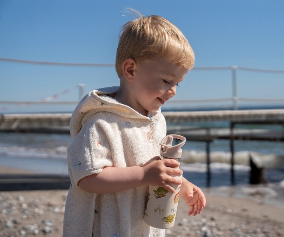 Dino Beach Stainless Steel Water Bottle, το οποίο κρατάει ένα παιδάκι
